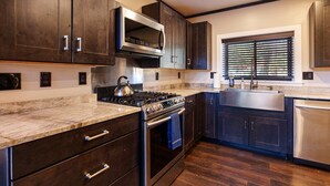 Une cuisine moderne avec des meubles de couleur bois foncé, une cuisinière en acier inoxydable et un four à micro-ondes encastré.