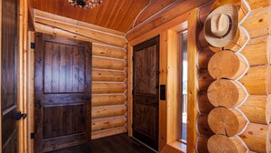 L’intérieur d’une cabane en rondins, avec des murs en bois, deux portes en bois et une fenêtre.