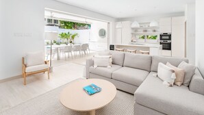 A modern living room with a sofa, coffee table, and a dining area with chairs and a table. - Porters Place 13: A one-of-a-kind experience await (Porters)