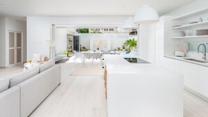 A modern kitchen with white cabinetry, a central island, and pendant lighting. - Porters Place 13: A one-of-a-kind experience await (Porters)