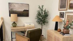 A cozy room with a desk, chair, and a small table with a lamp. There is a framed picture on the wall and a potted plant. - Private Hot Tub, Stunning Decor & Panoramic Lake Views with Free SDC Tickets (Kimberling City)