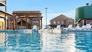 A swimming pool with lounge chairs, a wooden pergola, and a large water tank. - Private Hot Tub, Stunning Decor & Panoramic Lake Views with Free SDC Tickets (Kimberling City)
