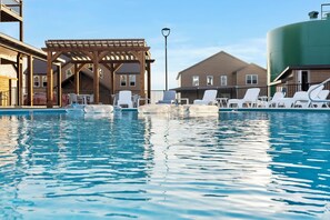 A swimming pool with lounge chairs, a wooden pergola, and a large water tank.