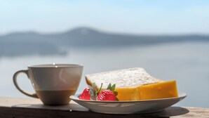 Una taza de café, una rebanada de queso y fresas en un plato.
