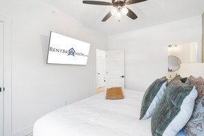 A bedroom with a bed, a ceiling fan, a mounted TV, and a door. - Private Hot Tub, Stunning Decor & Panoramic Lake Views with Free SDC Tickets (Kimberling City)
