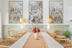 A dining room with a long table, chairs, and three large paintings on the wall. - Private Hot Tub, Stunning Decor & Panoramic Lake Views with Free SDC Tickets (Kimberling City)