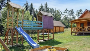 Un parque infantil con un tobogán, una estructura para escalar y un arenero con juguetes.