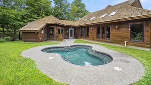 Una casa de madera de dos pisos con piscina en el jardín trasero.