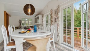 A dining area with a round table, white chairs, a blue pitcher, and a hanging light fixture. - 3 bedroom stunning home in Græsted (Græsted)