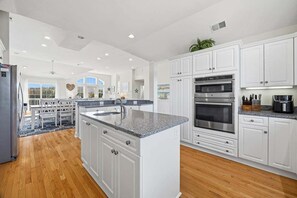 A spacious kitchen with white cabinetry, a central island, and a large oven.