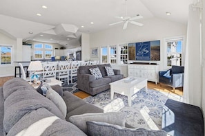 A spacious living area with a gray sofa set, a white coffee table, and a TV mounted on the wall.