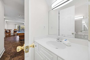 Ein Badezimmer mit einem weißen Waschbecken, einem großen Spiegel und einer Tür mit Messinggriffen.