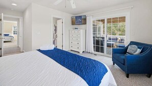 Une chambre à coucher avec un lit, une commode, une chaise et un ventilateur de plafond.
