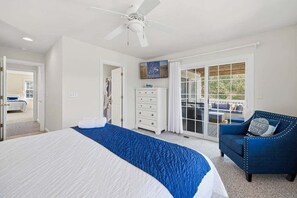Un dormitorio con cama, cómoda, silla y ventilador de techo.