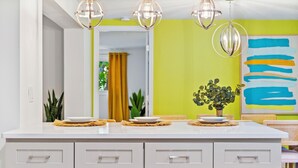 Una cocina moderna con armarios blancos, una isla grande e iluminación colgante.