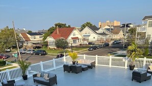 Terraza en la azotea con mobiliario de mimbre y barandilla blanca, con vistas a una zona residencial.