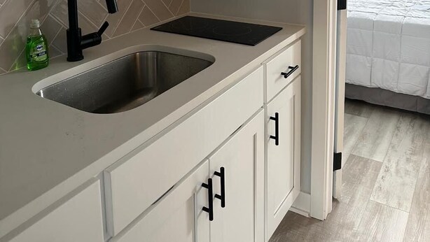 Una cocina compacta con microondas, lavamanos y armarios.
