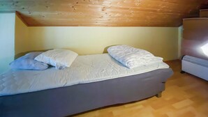 Un lit simple avec des oreillers et une couverture, un plafond en bois et un radiateur sur le côté droit.