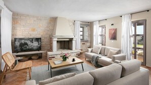 Una sala de estar con chimenea de piedra, un sofá, un televisor y un comedor.