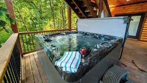 Un bain à remous sur une terrasse en bois, avec vue sur une forêt.
