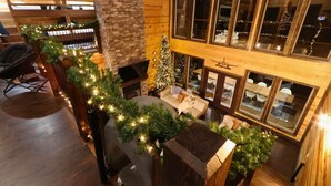Un intérieur chaleureux avec une cheminée, un sapin de Noël et un coin salon.