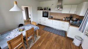Eine moderne Küche mit weißen Schränken, einer Holz Arbeitsplatte und einem Essbereich mit Tisch und Stühlen.