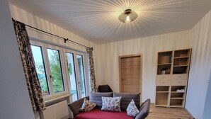 Ein gemütliches Zimmer mit einer Couch, einer roten Decke und einer Deckenleuchte.