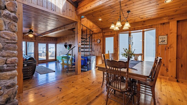 Un intérieur en bois comprenant une table et des chaises, un escalier et un mur en pierre.