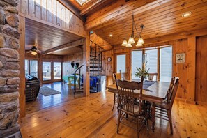 A wooden interior with a dining table and chairs, a staircase, and a stone wall. - Charming Cottage on the Bay and Golf Course with private patio and boat dock. (Sodus Point)