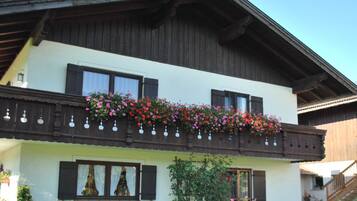 Ein zweistöckiges Gebäude mit einem Balkon, geschmückt mit Blumen und hängenden Dekorationen.