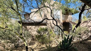 A desert landscape with sparse vegetation, a building with a balcony, and a clear blue sky. - Mountain View, Resort Style Condo (Tucson)