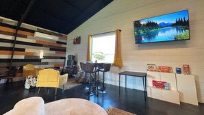 Ein modernes Wohnzimmer mit großem Fernseher, bequemen Sitzmöglichkeiten und einer dekorativen Wand.