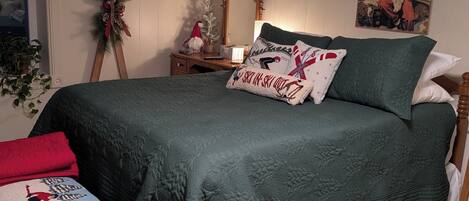 A bedroom with a bed, a bench, a mirror, a wall decoration, and a window.