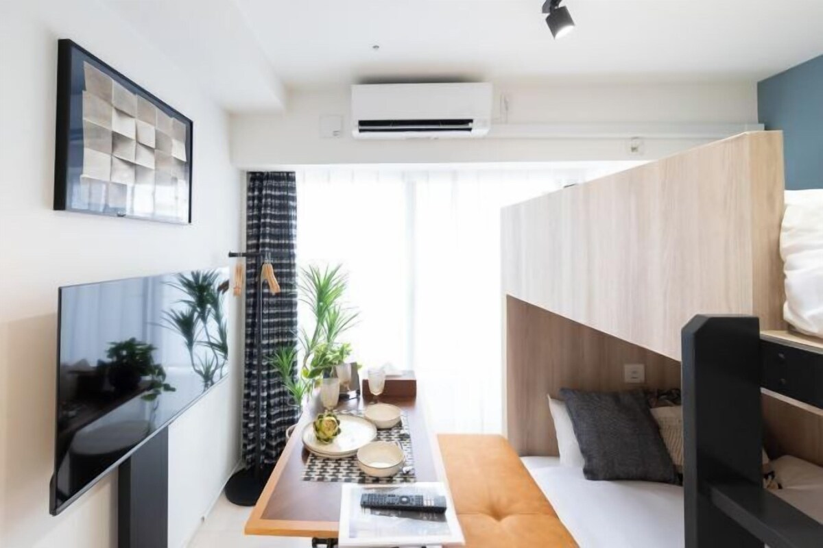 A modern living space with a flat-screen TV, a dining table with plates and glasses, a sofa, and a bunk bed.