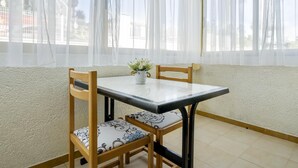 A dining area with a table and chairs, a potted plant, and sheer curtains. - Ground floor with pool and parking 100m beach (Cambrils)