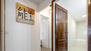 A hallway with a wooden door, a white wall with a framed artwork, and a light switch. - Ground floor with pool and parking 100m beach (Cambrils)
