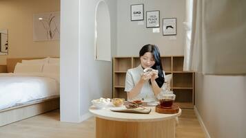 Una camera d'albergo moderna con un letto rifatto, un tavolo rotondo con cibo e bevande, e un'arredamento minimalista con citazioni motivazionali incorniciate al muro.