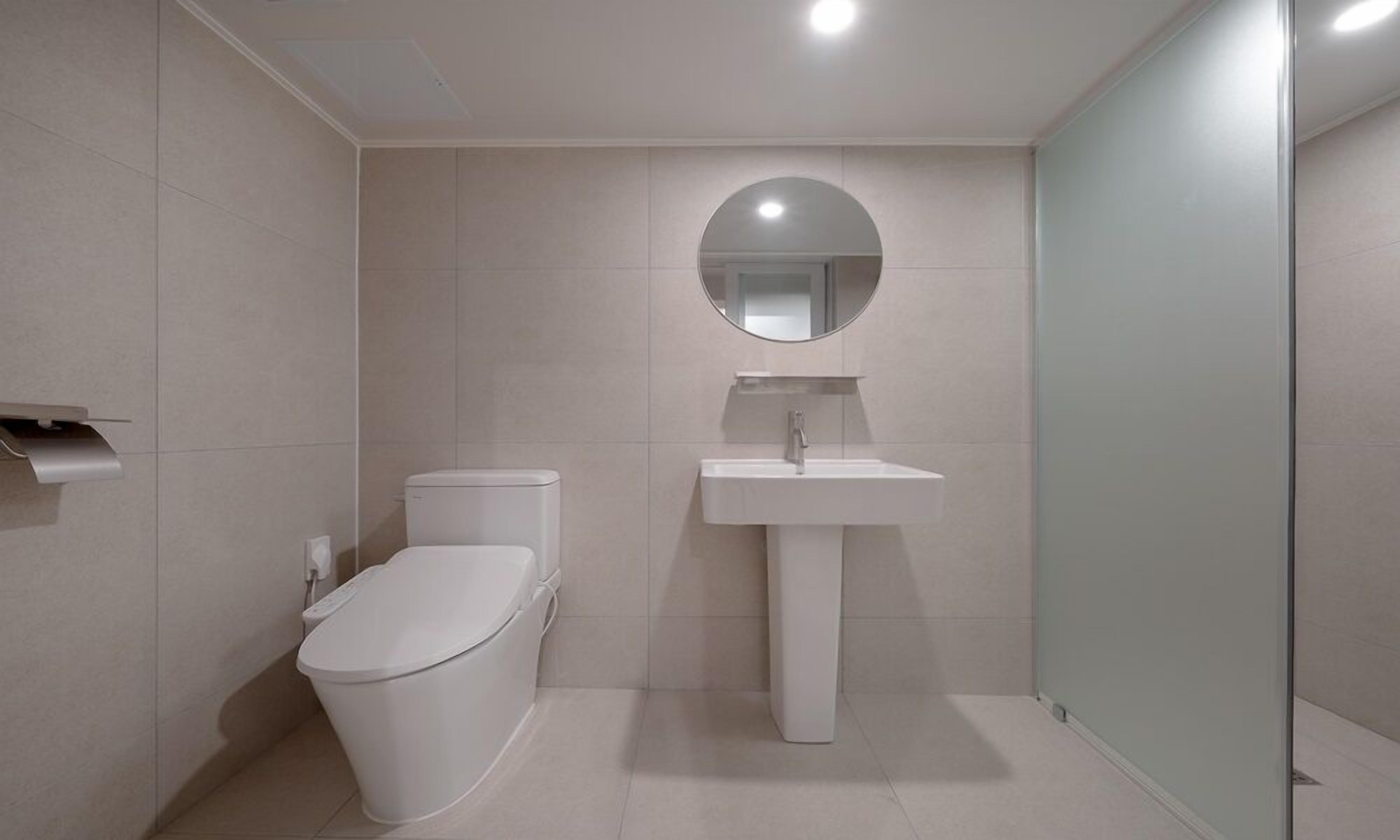 Un baño moderno con inodoro, lavamanos y espejo.