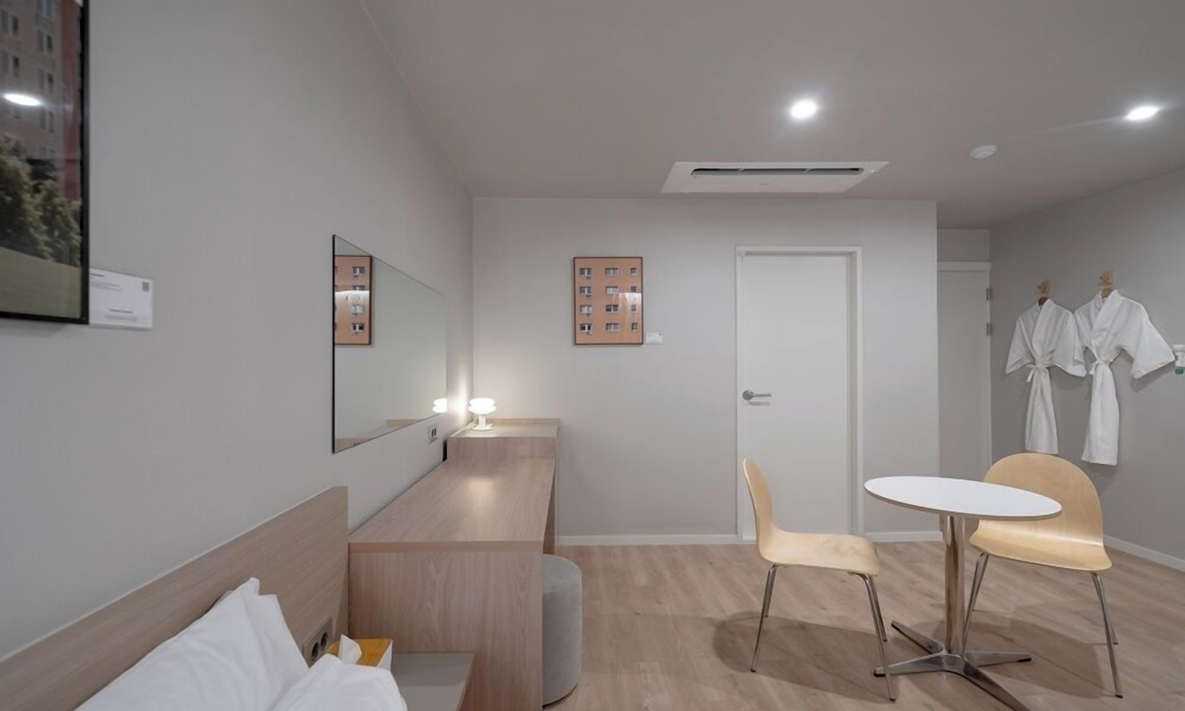 Una habitación de hotel moderna con una cama, un escritorio, una silla y una mesita.