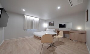 Una habitación de hotel moderna con cama, escritorio, silla, televisor y ventana con cortinas.