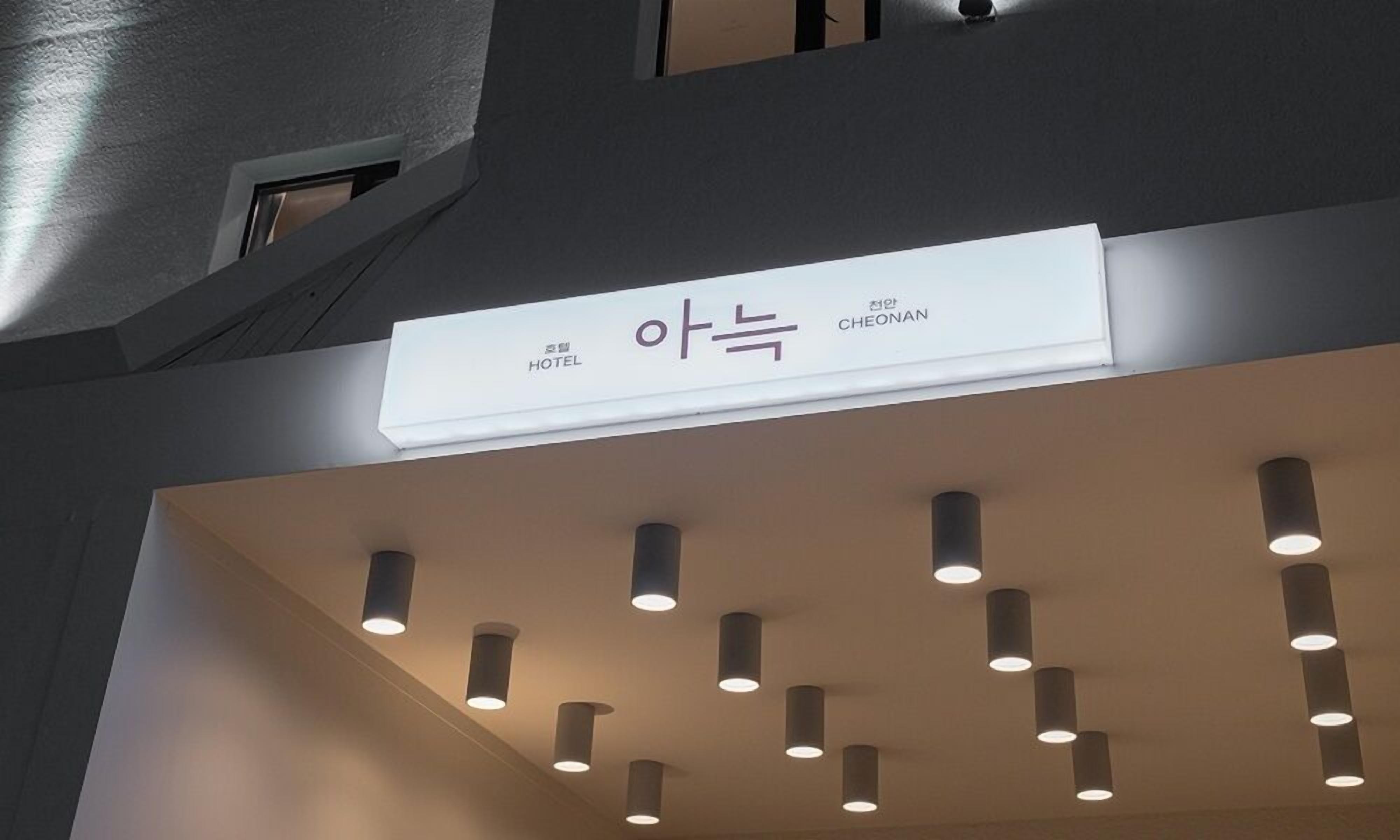 A hotel sign with Korean text and a modern ceiling with recessed lighting.
