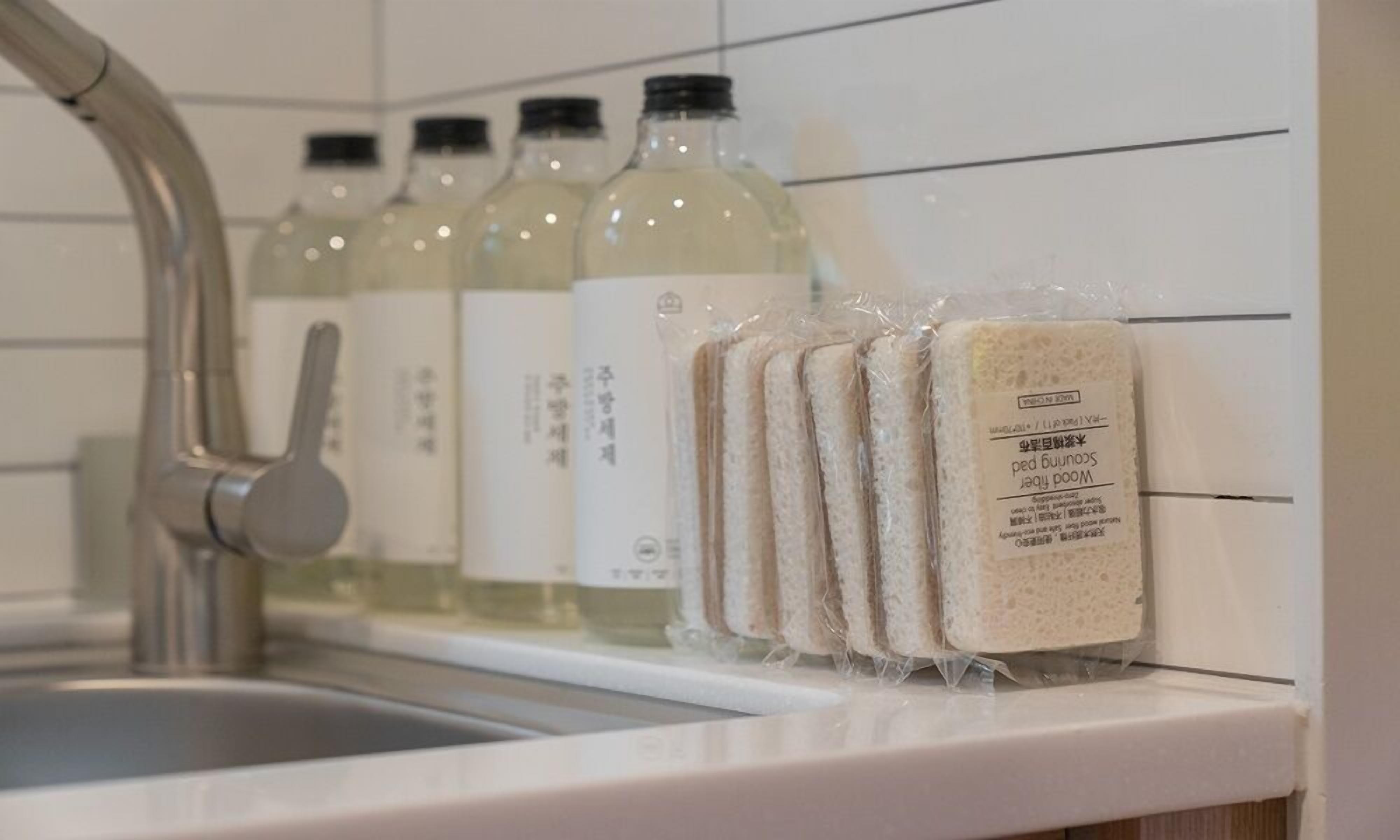 Un lavamanos de cocina con grifo, botellas de líquidos y barras de pan envasadas sobre la encimera.