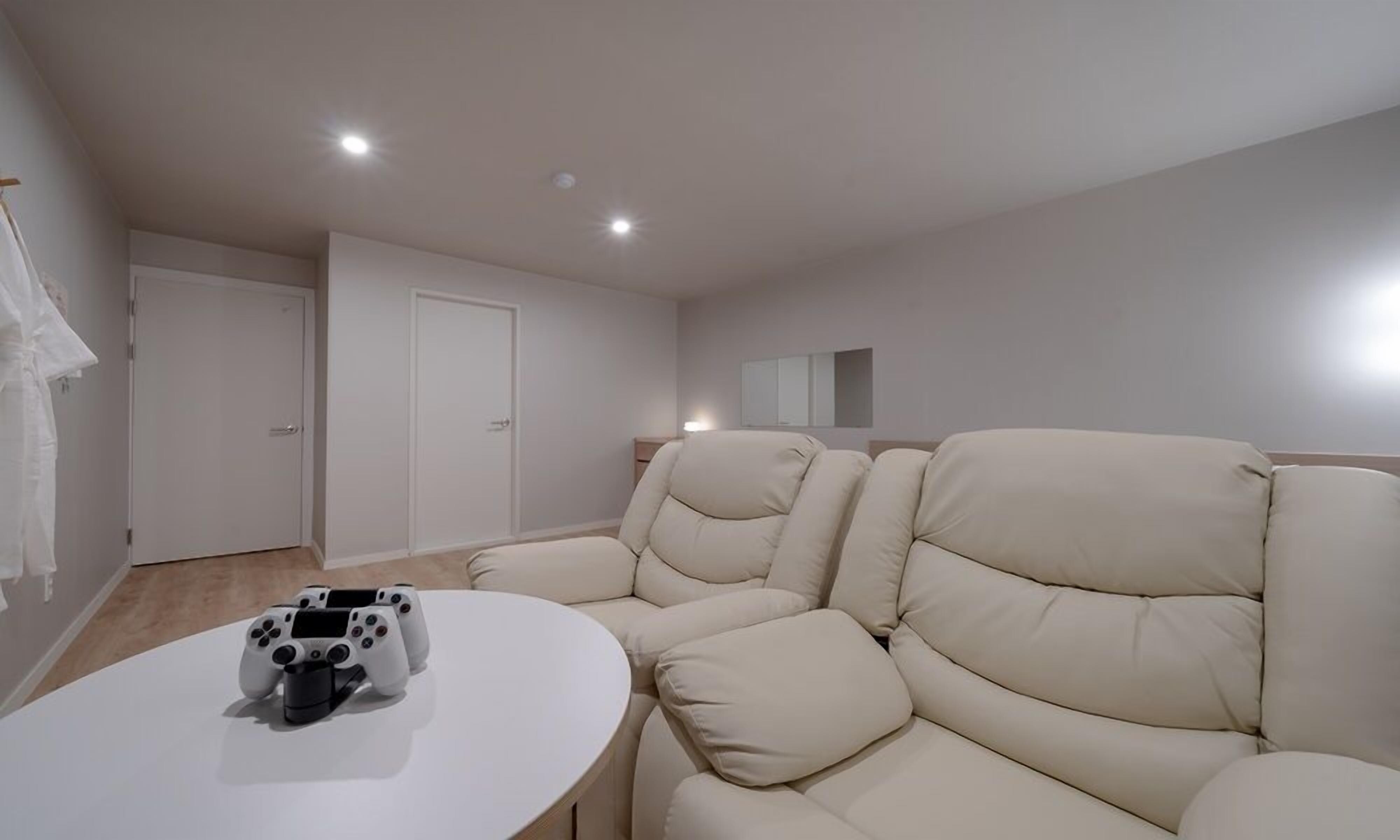 A modern living room with a beige sofa, a white coffee table, and a gaming console.