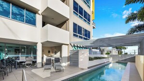 A modern building with a swimming pool, outdoor seating, and a covered area. - Nova Ocean Views Mooloolaba 2 Bedroom Apartment (Sunshine Coast)