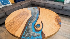 Una mesa de centro redonda de madera con un diseño ondulado en azul y gris.