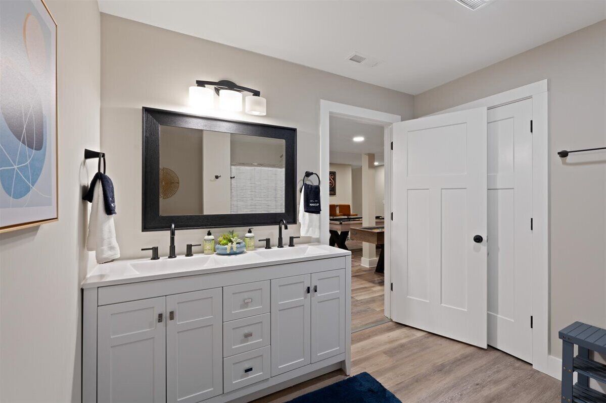 Une salle de bain moderne avec un grand miroir, un meuble-lavabo blanc et un tapis bleu foncé.