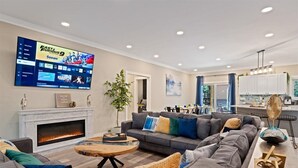 Una sala de estar moderna con chimenea, un televisor de pantalla plana grande y una zona de estar acogedora.