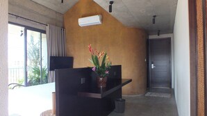 A modern hotel room with a concrete ceiling, a small black desk with a vase of flowers, a wicker chair, and a view of the outdoors. - Apartment for 2 people on 1st floor with 1 room and 1 bathroom -Hoi An Lifestyle (Hội An)
