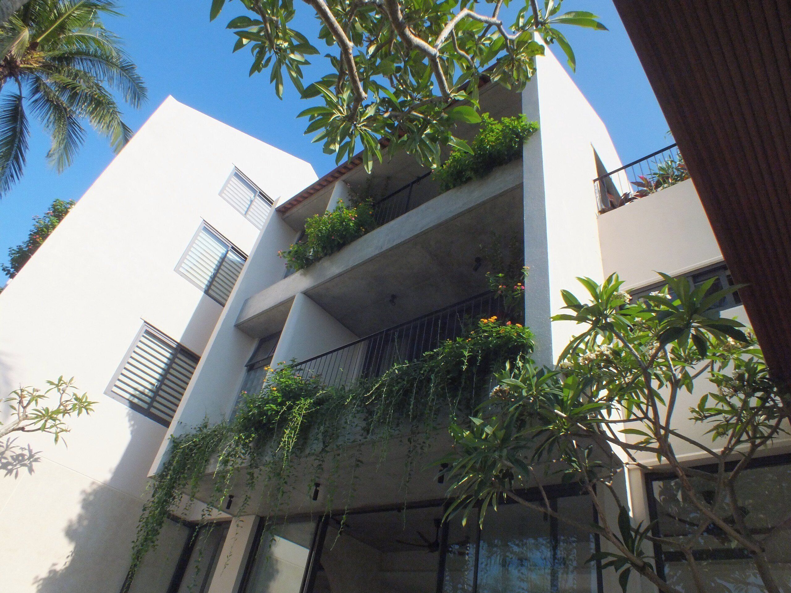 A multi-story building with balconies, some with plants.