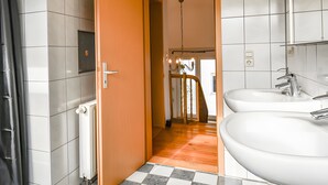 Een badkamer met twee wasbakken, een douche en een houten vloer.